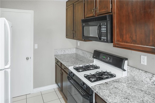 kitchen with white appliances, baseboards, and light tile patterned flooring