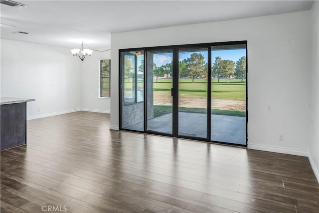unfurnished living room with plenty of natural light, a chandelier, dark wood-style floors, and baseboards