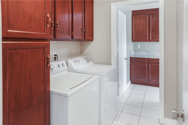 laundry area featuring washing machine and dryer, cabinet space, and light tile patterned floors