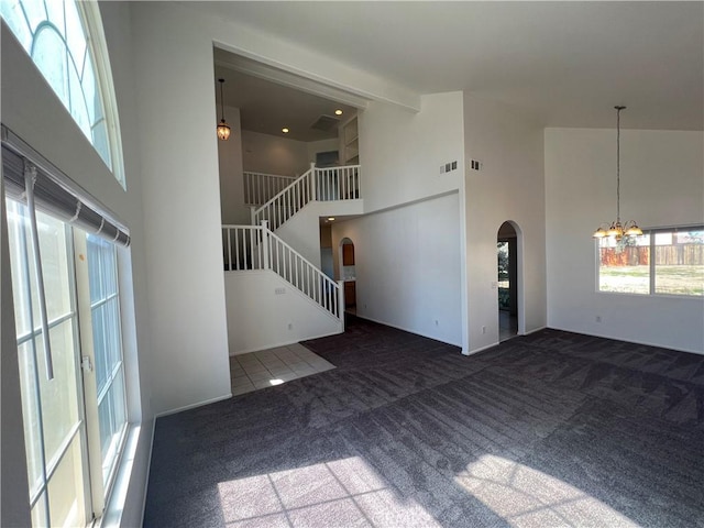 12418 Firefly Way, Victorville, CA 92392 - unfurnished living room featuring arched walkways, a high ceiling, a chandelier, carpet floors, and stairway