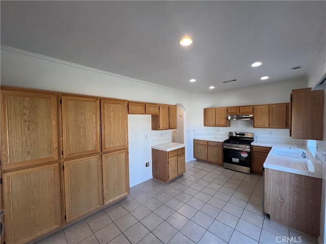 12418 Firefly Way, Victorville, CA 92392 - kitchen with stainless steel gas range, light tile patterned flooring, under cabinet range hood, recessed lighting, and arched walkways