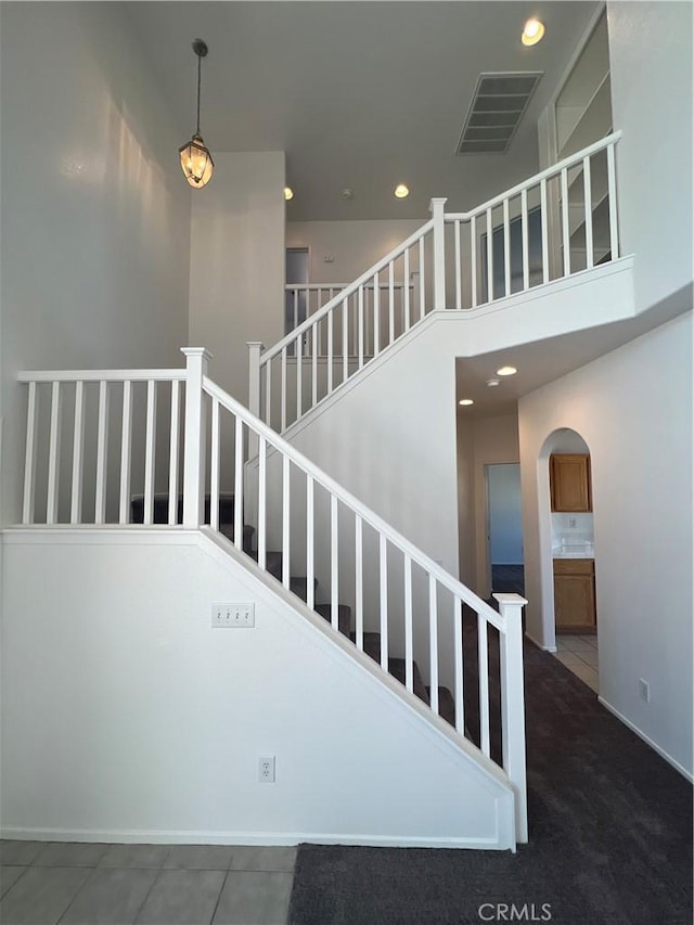 12418 Firefly Way, Victorville, CA 92392 - staircase with a high ceiling, arched walkways, recessed lighting, carpet flooring, and baseboards