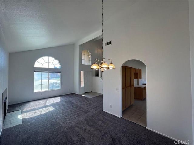 12418 Firefly Way, Victorville, CA 92392 - spare room with a chandelier, carpet flooring, arched walkways, a high ceiling, and a fireplace with flush hearth