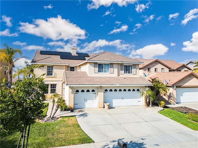 traditional-style home featuring stucco siding, concrete driveway, a garage, solar panels, and a tiled roof