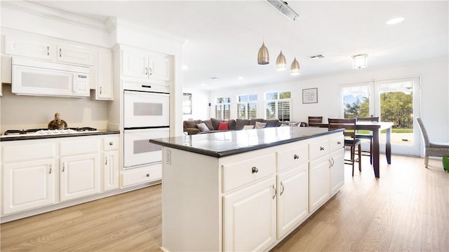 kitchen with white appliances, dark countertops, light wood-style flooring, recessed lighting, and a kitchen island