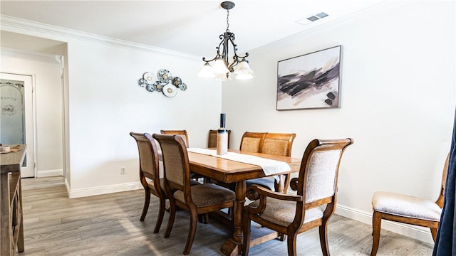 dining area featuring baseboards, ornamental molding, light wood-style floors, and a chandelier