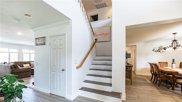 stairs featuring crown molding, wood finished floors, baseboards, a chandelier, and recessed lighting