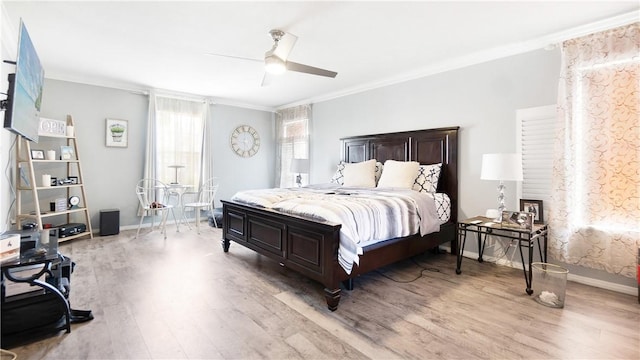 bedroom featuring light wood-style floors, ornamental molding, a ceiling fan, and baseboards