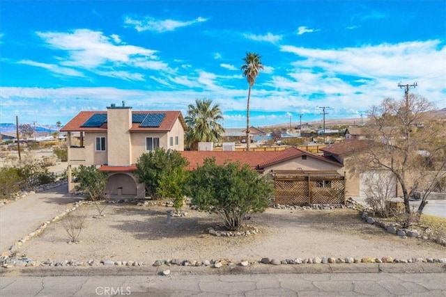 7565 Sherman Hoyt Ave Unit 29, Palms, CA 92277 - view of front of home with stucco siding, roof mounted solar panels, and a chimney