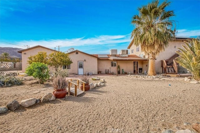 7565 Sherman Hoyt Ave Unit 29, Palms, CA 92277 - rear view of house featuring stucco siding, roof mounted solar panels, and stairway