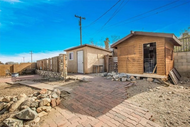 7565 Sherman Hoyt Ave Unit 29, Palms, CA 92277 - back of property featuring an outbuilding, a fenced backyard, and a patio area