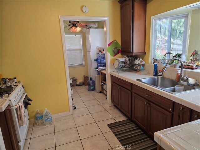 519 N Sloan Ave, Compton, CA 90221 - kitchen featuring tile countertops, white gas stove, a sink, and light tile patterned flooring