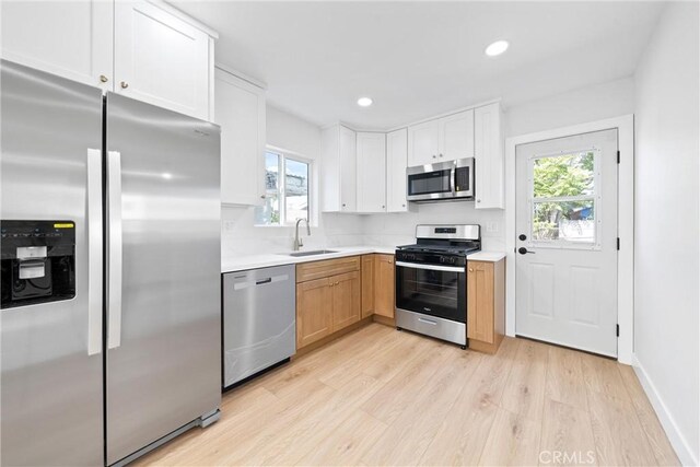 9613 Wilmington Ave, Los Angeles, CA 90002 - kitchen featuring appliances with stainless steel finishes, a sink, light wood-style floors, light countertops, and healthy amount of natural light