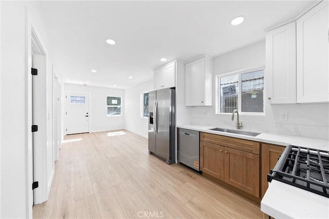 9613 Wilmington Ave, Los Angeles, CA 90002 - kitchen featuring stainless steel appliances, a sink, light countertops, brown cabinets, and light wood-style floors