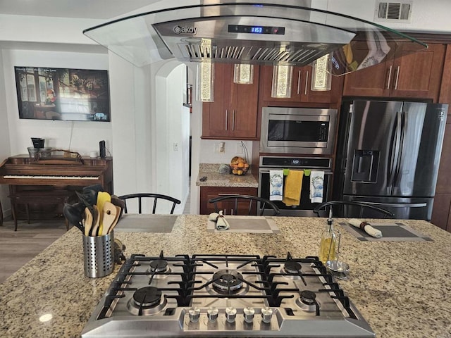 43075 Corte Fresca, Temecula, CA 92592 - kitchen featuring stainless steel appliances, arched walkways, light stone counters, and wood finished floors