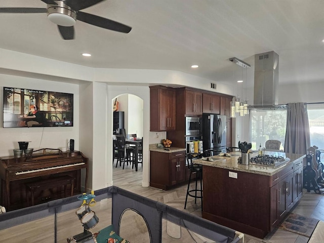 43075 Corte Fresca, Temecula, CA 92592 - kitchen with stainless steel appliances, arched walkways, a ceiling fan, a kitchen bar, and light wood-type flooring