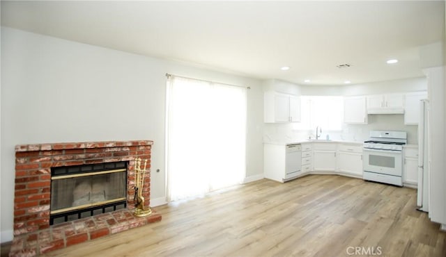 5538 Katrina Pl, Palmdale, CA 93552 - kitchen with white appliances, a sink, light wood finished floors, a brick fireplace, and recessed lighting