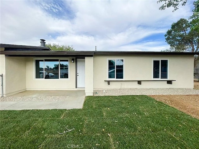 back of house featuring a lawn, stucco siding, and a patio area