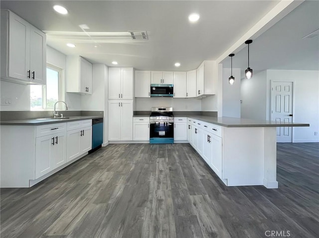 40294 Fieldspring St, Palmdale, CA 93591 - kitchen featuring appliances with stainless steel finishes, a peninsula, dark wood-type flooring, dark countertops, and white cabinetry