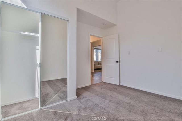 unfurnished bedroom featuring carpet floors, baseboards, and a closet