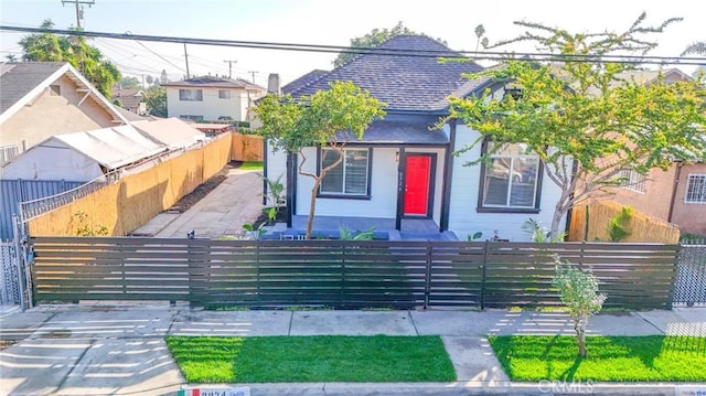 view of front facade with a fenced front yard and roof with shingles