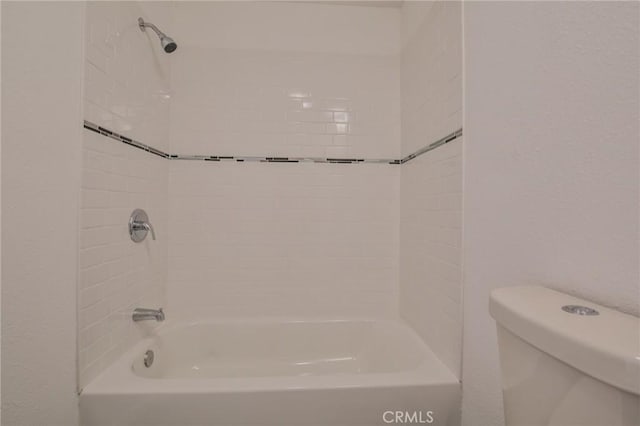 full bathroom featuring toilet, washtub / shower combination, and a textured wall