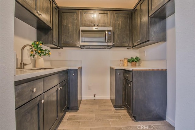 bar featuring stainless steel microwave, a sink, baseboards, and wood finish floors