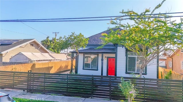 view of front of home with a fenced front yard and a shingled roof
