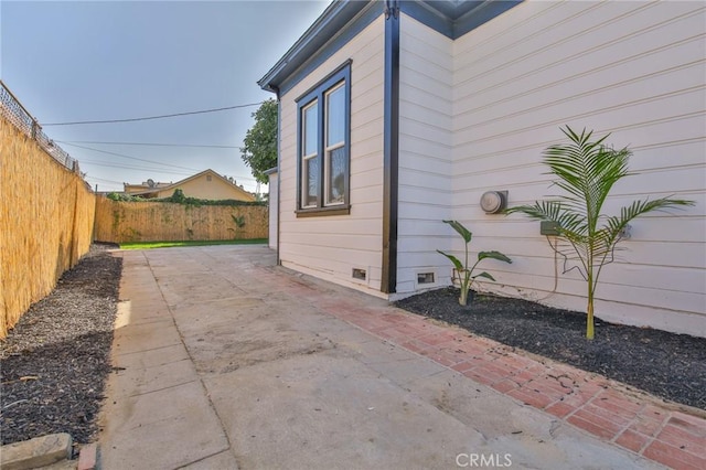 view of side of home featuring a patio, a fenced backyard, and crawl space