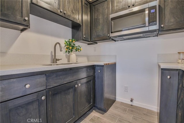 kitchen featuring a sink, light countertops, baseboards, and wood finish floors