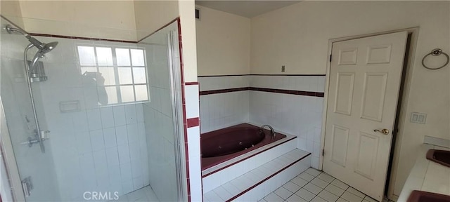 bathroom with a stall shower, a bath, tile patterned flooring, and tile walls
