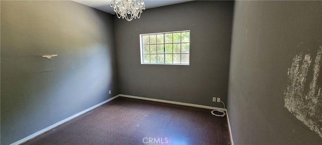 unfurnished room with a chandelier and baseboards