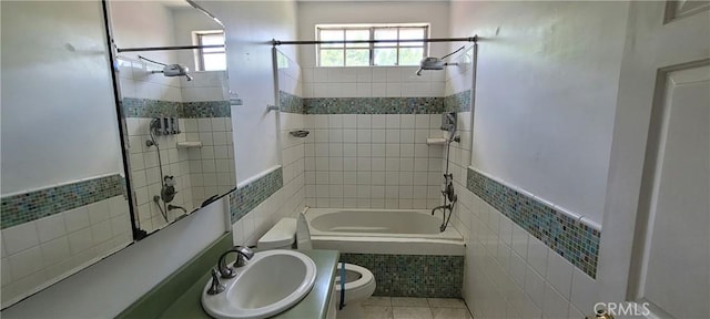 full bath featuring tile walls, a sink, toilet, tiled shower / bath, and tile patterned flooring