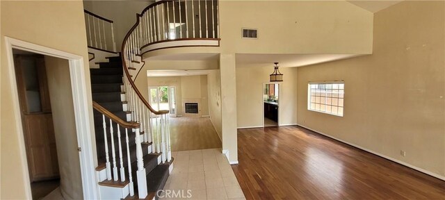 foyer entrance with wood finished floors, a towering ceiling, stairway, and baseboards