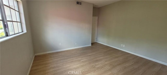 spare room with light wood-type flooring, plenty of natural light, and baseboards