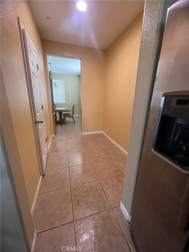 corridor featuring light tile patterned floors and baseboards