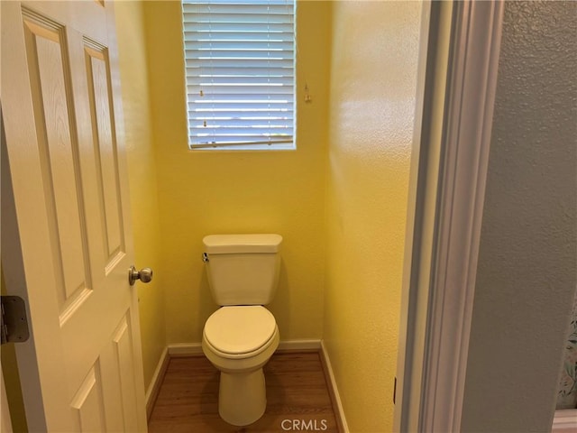 bathroom featuring wood finished floors, toilet, and baseboards