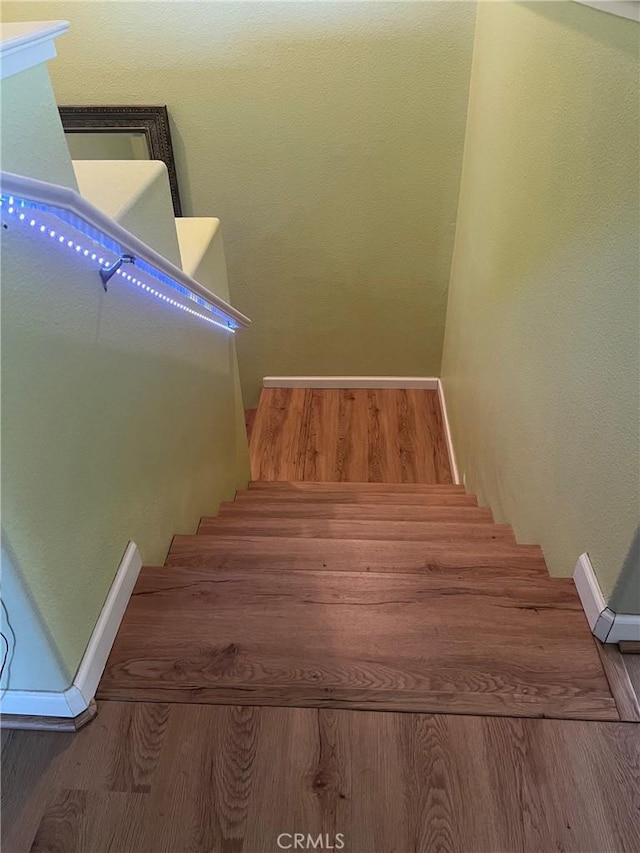 stairway with wood finished floors and baseboards