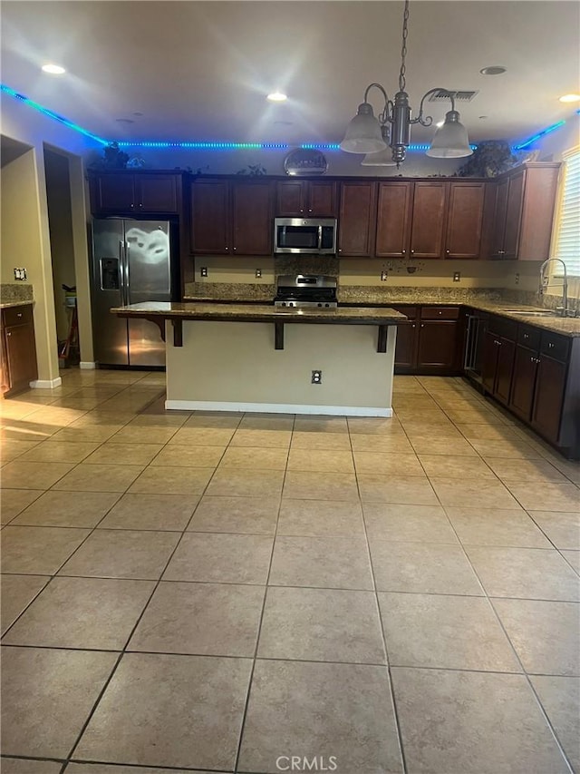 kitchen featuring appliances with stainless steel finishes, a sink, a breakfast bar area, and light tile patterned flooring
