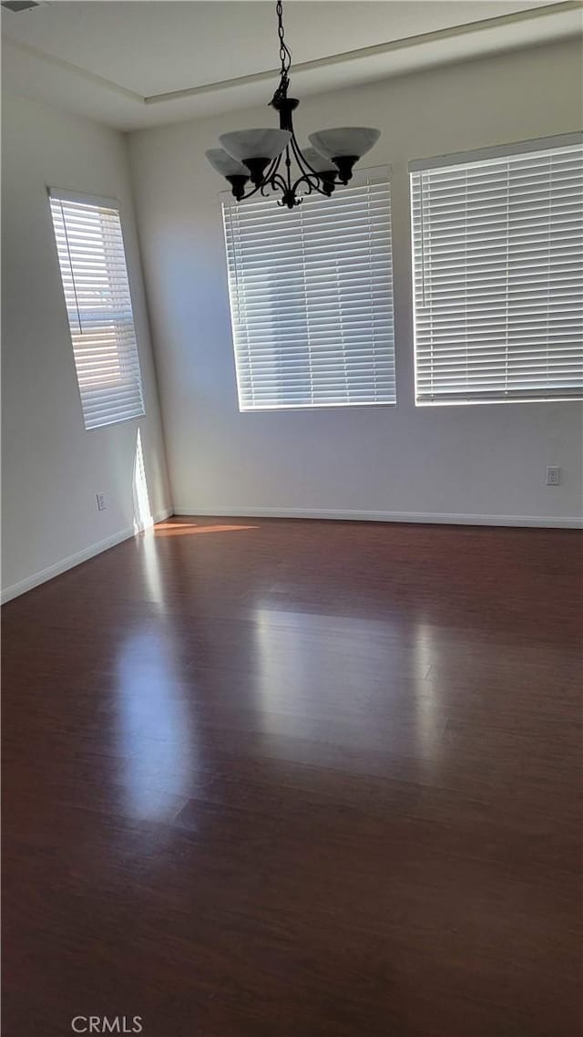 29746 Maxmillian Ave, Murrieta, CA 92563 - empty room with dark wood-style flooring, a chandelier, and baseboards