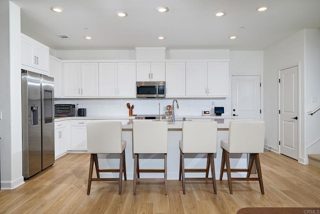 kitchen with stainless steel appliances, decorative backsplash, light wood finished floors, light countertops, and recessed lighting