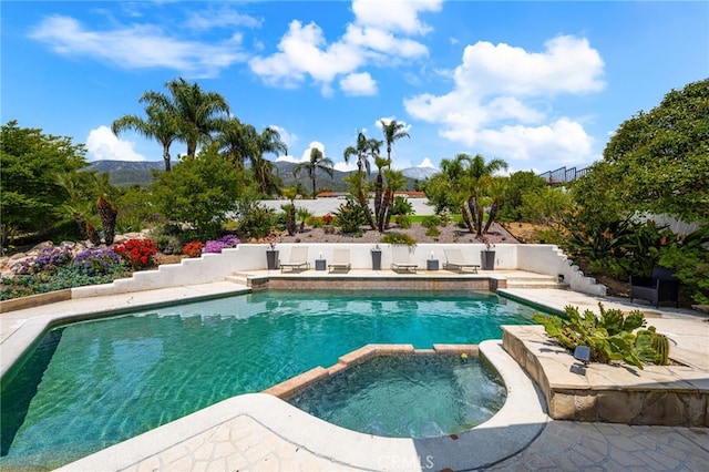 view of pool with a mountain view, a pool with connected hot tub, and a patio