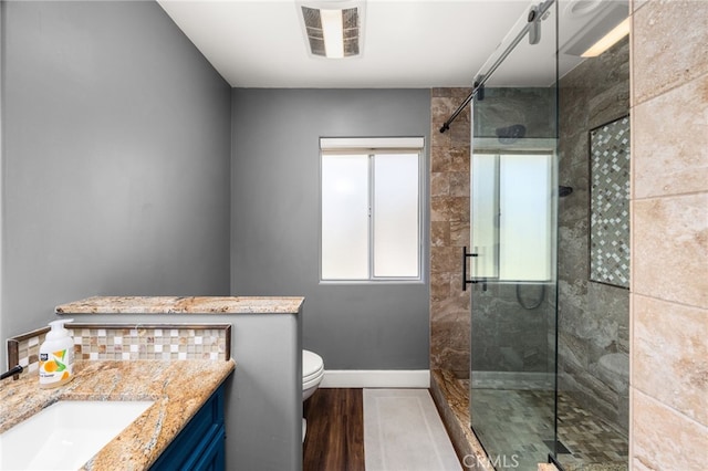 bathroom with a shower stall, toilet, vanity, and baseboards