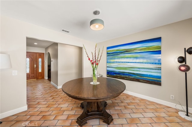 dining area featuring baseboards, light tile patterned flooring, arched walkways, and recessed lighting