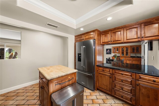 kitchen with high end refrigerator, light tile patterned floors, recessed lighting, brown cabinetry, and crown molding