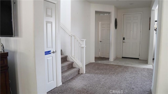 entrance foyer featuring light colored carpet, stairs, light tile patterned flooring, and baseboards