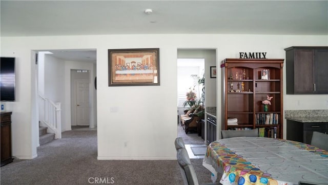carpeted dining space with stairs and baseboards