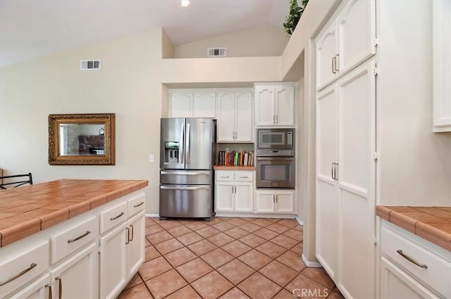 22523 White Sage St, Corona, CA 92883 - kitchen with stainless steel appliances, vaulted ceiling, tile countertops, white cabinets, and light tile patterned flooring