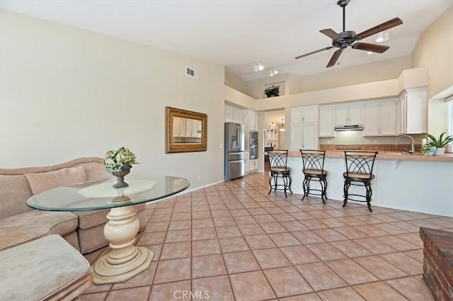 22523 White Sage St, Corona, CA 92883 - kitchen featuring stainless steel fridge, open floor plan, a peninsula, under cabinet range hood, and white cabinetry