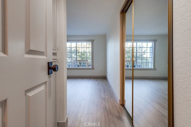 hall with light wood-type flooring and baseboards